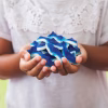 Close-up of a person holding a handful of Blue Sharks Gummy Candy, highlighting the bold blue hue and shark shapes