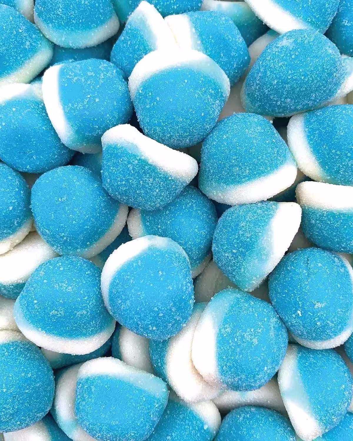 Closeup of a pile of Blue Raspberry Gummies with a fine crystal sugar coating, showcasing their vibrant blue color and chewy texture